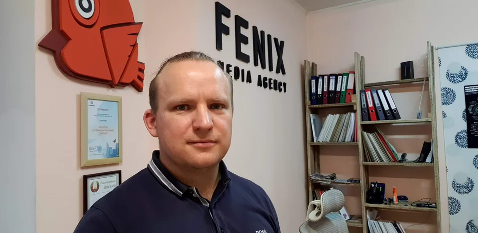 Дмитрий Ленько в рабочем офисе рядом с сертификатами